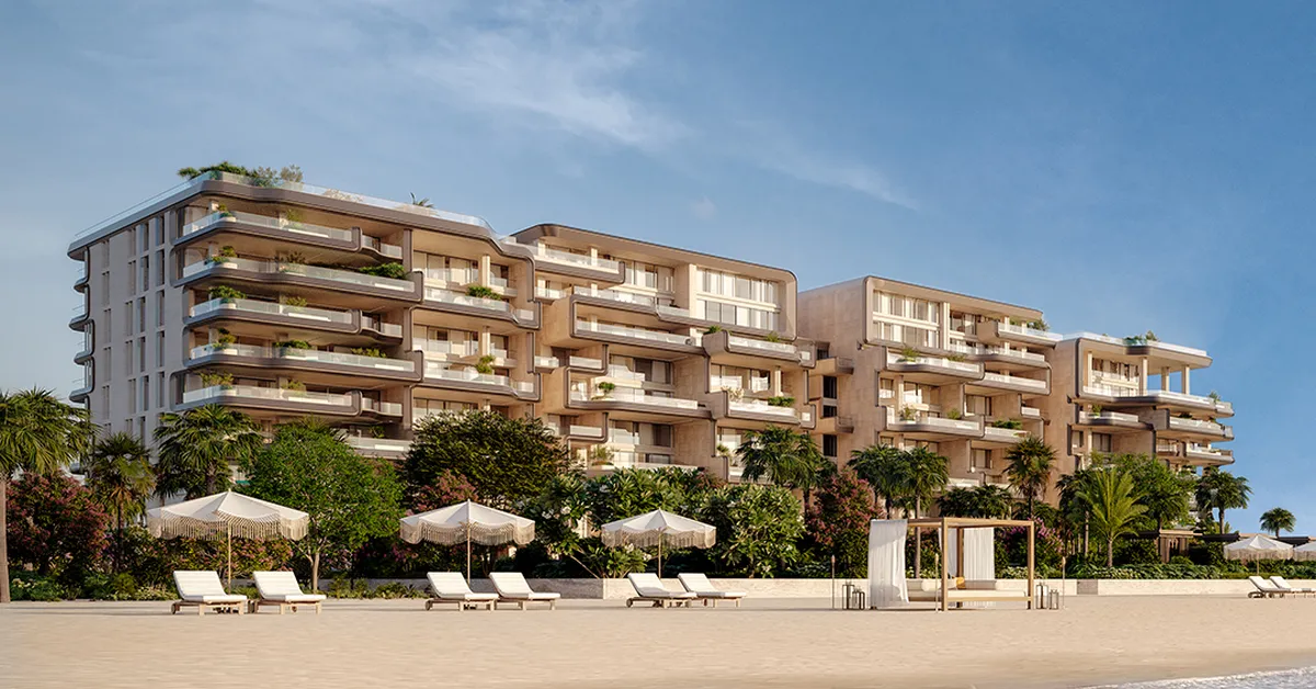 نمای ساحلی مجتمع The Alba Residences با سایبان و صندلی‌های ساحلی